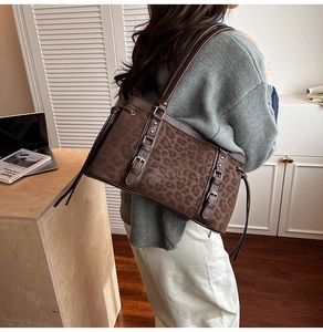 Close-up of leopard print suede tote with dark brown leather straps and metal buckle