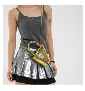 Detail of a mini gold bucket bag with crocodile texture and sleek bead chain strap