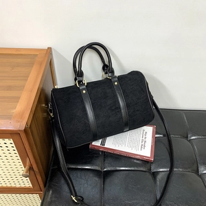 Detail of black faux suede Boston bag with gold hardware and smooth leather handles