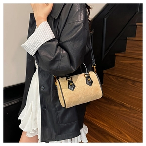 Detail view of khaki suede Boston bag with quilted stitching and black patent leather accents