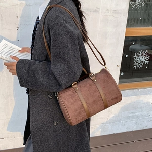 Detail of a brown faux suede boston bag showing the matte texture and golden hardware