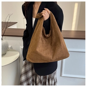 Detail of vintage brown suede tote bag with stylish knotted handle and retro minimalist design