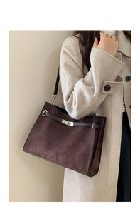 Detail of dark brown matte suede tote bag with silver buckle and leather strap on a model