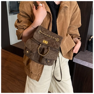 Close-up of quilted dark brown velvet backpack with gold chain and twist lock details