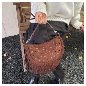 Detail van bruine suède maanvormige tas met zilveren oogjes en lange decoratieve franjes