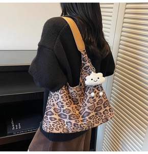 Detail of leopard print tote bag featuring a white cloud plush charm on brown strap