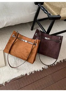 Detail of suede tote bags in caramel and coffee tones with elegant silver metal twist locks
