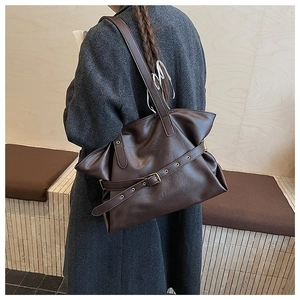 Detail of dark brown leather tote bag showing vintage texture and metal buckle strap