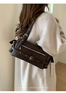 Detail of dark brown faux leather pillow bag with silver buckle and metal eyelet accents