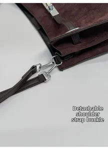 Detail of silver clasp and removable leather strap on brown suede tote bag