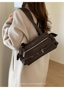 Brown retro shoulder bag with silver zipper and buckle detail on light coat background