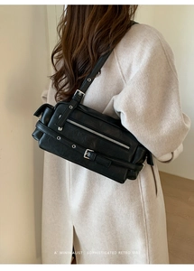 Detail of vintage black leather shoulder bag featuring silver buckles and eyelet straps