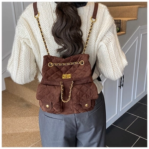 Detail eines braun gesteppten Rucksacks mit goldenem Drehverschluss und Kettenriemen