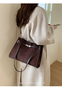 Close-up of a large dark brown suede tote bag with leather straps and metal buckle detail