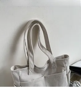 Gros plan des bandoulières et des détails de couture de ce sac fourre-tout en velours côtelé
