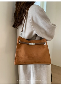 Retro brown suede tote bag with silver twist lock shown on a minimalist coat