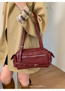Detail of burgundy retro shoulder bag featuring silver zippers and buckle accents