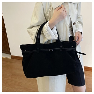 Detalle del bolso tote de ante negro con hebilla de cinturón y acabado mate suave