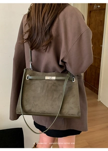 Close-up of minimalist dark olive green suede shoulder bag with gold twist lock buckle