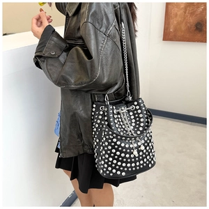 Détail du sac seau en cuir noir avec clous argentés, chaîne épaisse et breloque perle