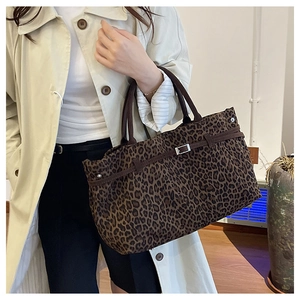 Detalle del bolso tote con estampado de leopardo y asas de cuero marrón con hebilla