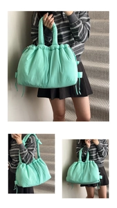 Detail of mint green puffy nylon tote bag with drawstring texture and soft shoulder straps