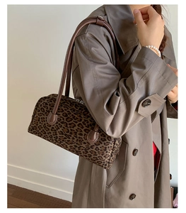 Leopard print baguette shoulder bag shown on model with brown coat and dual handles