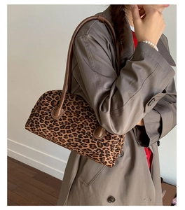 Leopard print baguette bag with brown leather strap styled on a khaki trench coat