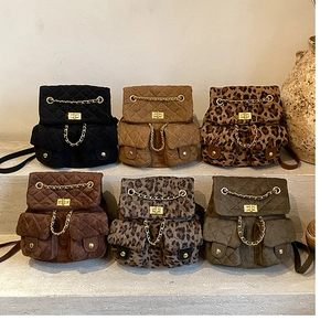 Quilted leopard and solid color mini backpacks with gold chain decoration on stone steps