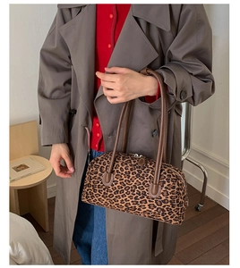 Detail of leopard print baguette bag with brown leather straps and double zipper closure
