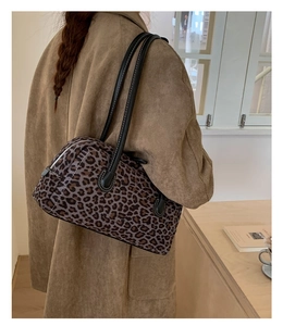 Detail of leopard print baguette bag featuring black leather handles and silver hardware