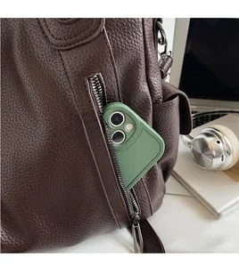 Detail shot of the leather bag's side zipper pocket holding a smartphone for storage