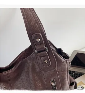 Macro detail of silver hardware rivets and leather strap on dark brown shoulder bag
