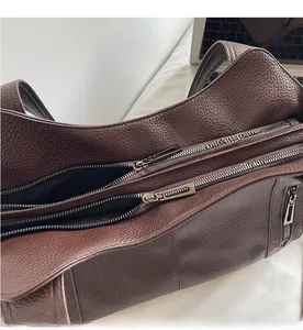 Detail of smooth metal zipper and premium lychee texture on brown leather tote bag