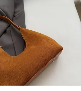 Detail of brown suede handbag featuring reinforced metal rivets and premium zipper closure