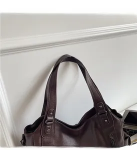 Detail of dark brown pebble leather bag with sturdy handles and metallic hardware