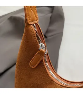 Close-up of smooth metal zipper and premium suede texture on the caramel shoulder bag