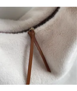 Vue détaillée de la texture pelucheuse crème avec long tirette de zip en cuir marron