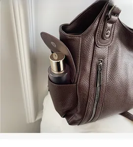 Detail view of brown lychee grain leather tote with side magnetic flap pocket and zipper
