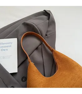 Brown suede crescent bag showcased over a grey blazer for a modern casual chic look