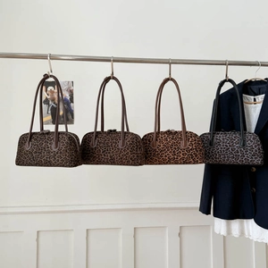 Série de sacs Boston imprimé léopard en quatre couleurs à côté d'un blazer bleu marine