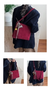 Dettaglio della borsa a spalla in pelle scamosciata bordeaux con nappe e charm smiley