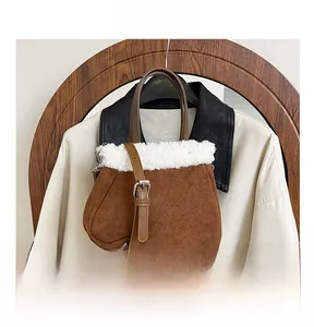 Close-up of brown suede handbag featuring white faux shearling trim and slim shoulder strap
