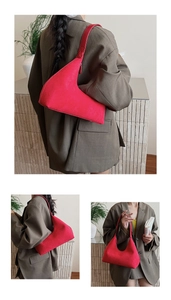 Close-up of red suede hobo bag with asymmetric curved design and wide shoulder strap