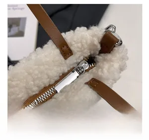 Detail showing smooth silver metal zipper and soft white plush fabric of the handbag