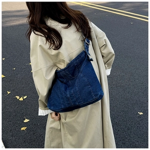 Detail van vintage denim halve maan tas met verticale stiksels en verstelbare gesp