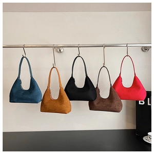Detail showing five colors of suede half-moon underarm bags hanging on S-hooks