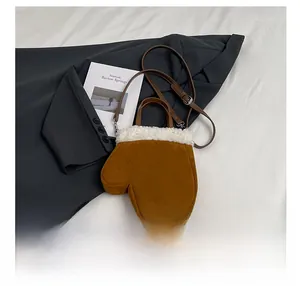 Detail shot of brown suede glove-shaped bag with white faux shearling trim on grey blazer