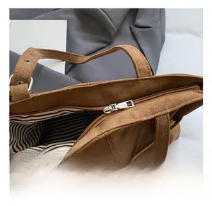 Détail du sac cabas en daim marron avec zip argenté et doublure intérieure rayée