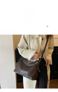 Detail of dark brown leather hobo bag with woven charm and decorative knot strap